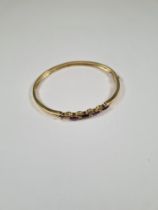 Unmarked yellow gold hinged bangle with decorative panel with 4 marquis shaped amethyst and 8 small