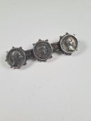 White metal bar brooch inset with three Roman coins