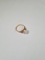 14ct gold dress ring with central pearl and a round cut garnet either side in raised scrolling mount