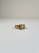 9ct yellow gold dress ring with central oval mixed cut peridot, and band decorated Greek key design,