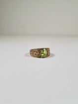 9ct yellow gold dress ring with central oval mixed cut peridot, and band decorated Greek key design,