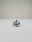 9ct yellow gold dress ring with pear shaped blue topaz with decorative shoulders in the form of leav