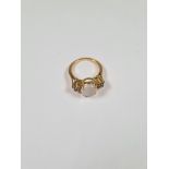 Unmarked yellow gold dress ring with central circular cabouchon moonstone and 4 small round cut diam
