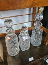 A pair of round glass decanters and one other square example