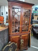 A carved corner cabinet with 2 glazed doors