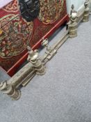 An ornate brass fender, adjustable, decorated with Grecian style swags and tails