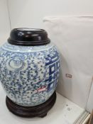 An antique Chinese blue and white ginger jar with wooden stand and lid, the jar 23cm