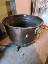 An old riveted copper log bin on brass paw feet, 45.5cms diameter
