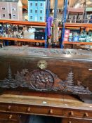 A carved oriental camphor wood blanket box decorated figures in landscape, 116.5cms
