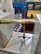 A modern brass plated telescope on folding tripod base