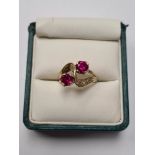 14K yellow gold cross over design ring with 2 round cut rubies, each 5.5mm diameter, on textured mou