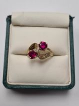 14K yellow gold cross over design ring with 2 round cut rubies, each 5.5mm diameter, on textured mou