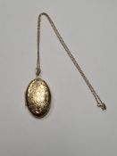 9ct gold fine chain hung with a large oval 9ct gold locket decorated with flowers, marked 375, appro