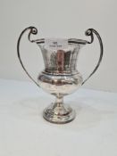 A silver trophy cup of baluster form, having two handles, raised pedestal base and engraved name bod