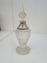 A pretty large scent bottle having silver collar and cut glass body. Decorative finial of pointed fo