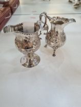 A very decorative silver creamer having inner beaded border, embossed design of fruit and a vacant c