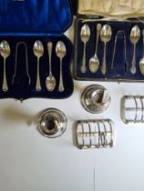 A cased set of decorative silver spoons and tongs, two silver toast racks by Hukin and Heath, a pair