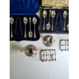 A cased set of decorative silver spoons and tongs, two silver toast racks by Hukin and Heath, a pair