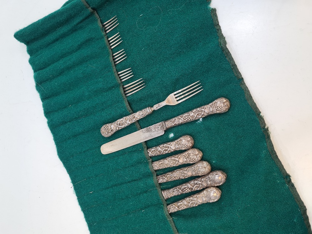 A set of six Victorian silver fruit knives and forks, with heavily embossed handles of vines and gra