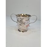 A large Georgian silver two handled cup having gilt interior and embossed body of flowers, in low re