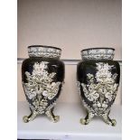A pair of early 20th Century vases having raised floral decoration on three feet, 37.5cms