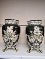 A pair of early 20th Century vases having raised floral decoration on three feet, 37.5cms