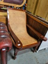 A mahogany steamer style chair having cane upholstery on turned front legs with folding leg rests
