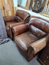 A pair of brown leather armchairs on square feet, (some tears)