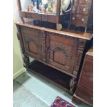 A reproduction carved oak cupboard having two doors and shelf below, 122cms