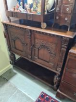 A reproduction carved oak cupboard having two doors and shelf below, 122cms