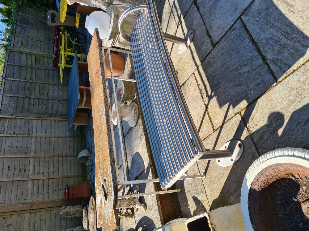 A garden table having wooden top and a modern tubular metal seat