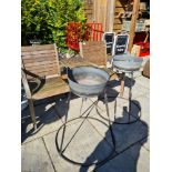 A modern garden seat having central table and 2 planters on wrought iron stands