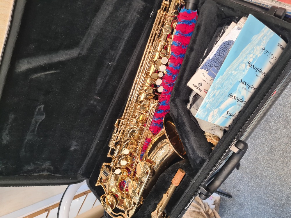 A Yamaha Saxophone in fitted case with related books and music stand