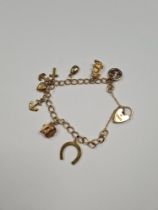 9ct yellow gold charm bracelet 8 gold charms, all 9ct gold including typewriter, horse shoe, anchor,