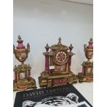 An early 20th Century French gilt metal clock garniture having porcelain panels decorated figures an