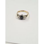 18ct yellow gold dress ring with central oval faceted sapphire with a round cut diamond to each side
