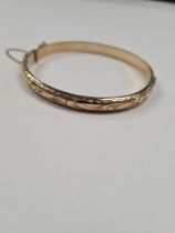 9ct yellow gold hinged bangle, the top engraved foliate design, with Safety chain, marked 375, Birmi