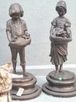 A pair of bronze sculptures of boy and girl with puppies and kittens on round base, stamped Lancini,