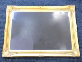 A rectangular gilt framed mirror in foliate moulded frame with bevelled plate. (35in x 25.5in)