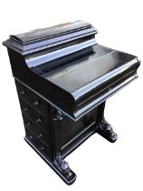 A Victorian ebonised davenport, the desk with arched stationary compartment and piano hinged lid