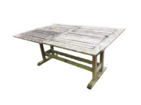An extending teak garden table, the slatted top with folding central leaves and a hole for a