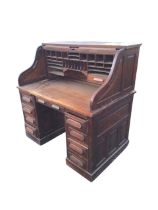 An Edwardian oak roll-top desk, the rectangular slatted tambour opening to pigeonholes and