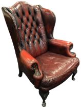 A Georgian style leather wing armchair, the arched button-upholstered back with curved wings and