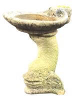 A composition stone garden bird bath, the scallopped shaped bowl raised on dolphin tail support with