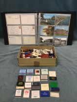 A collection of postcards in an album - mainly topographical; and a collection of match cases - some