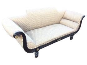 A regency ebonised upholstered sofa, the shaped back above a rectangular seat flanked by outscrolled