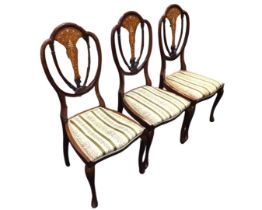 A set of three Edwardian mahogany salon chairs, the shield shaped backs with foliate marquetry