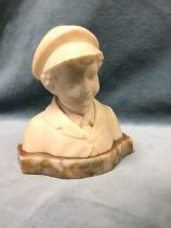 An Edwardian white marble portrait bust of a young boy wearing a suit and peaked cap, on a shaped