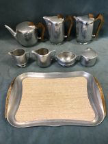 An eight-piece 70s Piquot Ware tea and coffee set on a tray, stylistically moulded with wood