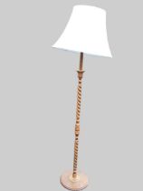 A beech standard lamp, the turned and barleytwist column on a circular moulded base with bun